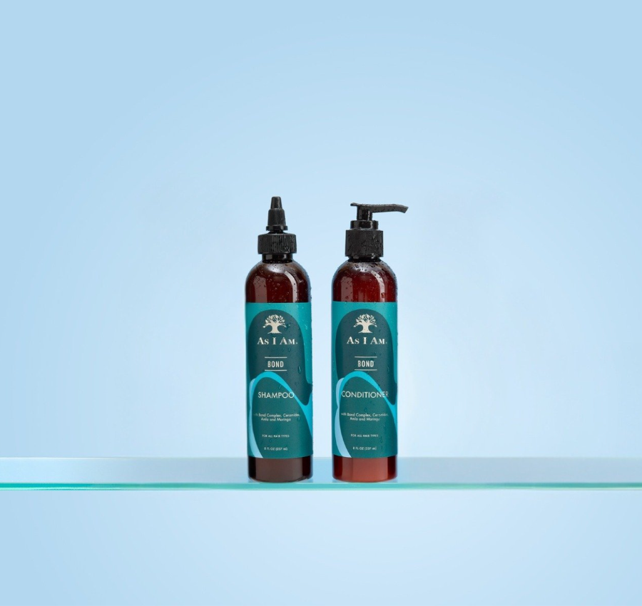 Deux bouteilles de shampooing et après-shampooing As I Am sur une surface claire avec un fond bleu clair