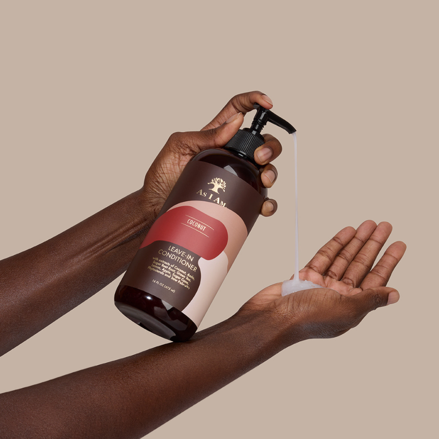 Hand, die eine Flasche Leave-in-Conditioner hält, vor beigem Hintergrund