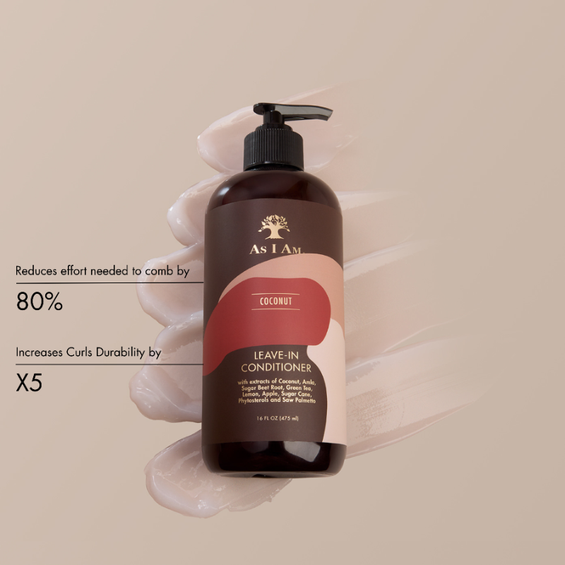 زجاجة بنية اللون من بلسم As I Am Coconut Leave-In Conditioner ممسوكة بيد على خلفية بيج