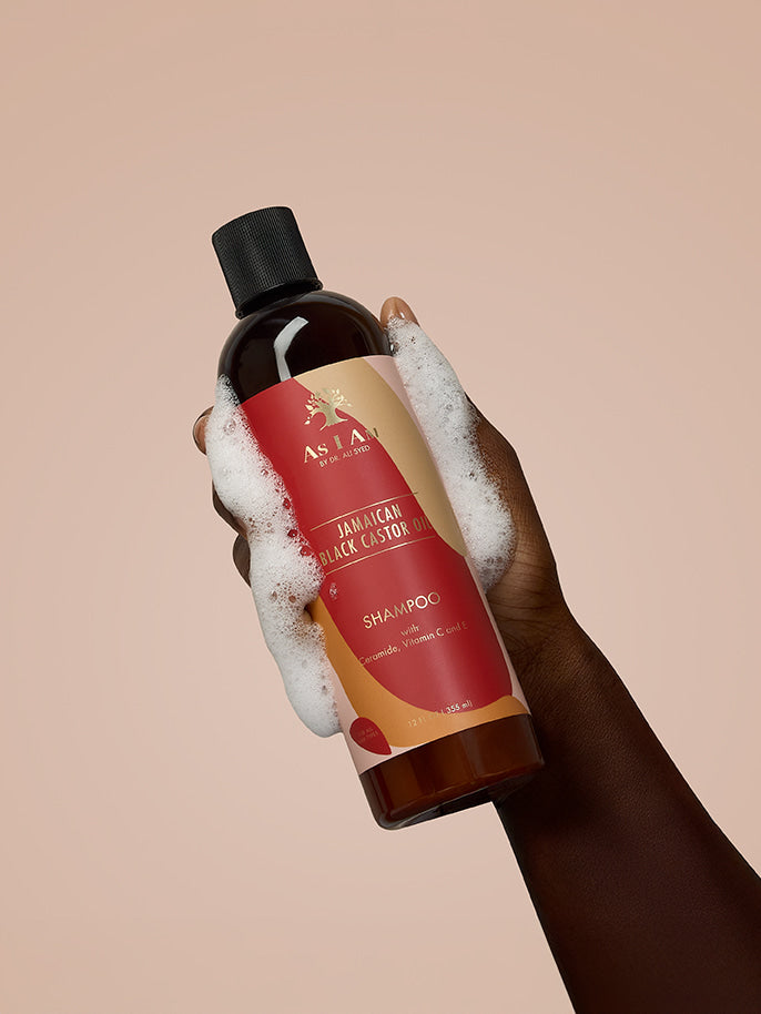 As I Am Jamaican Black Castor Oil Shampoo — portrait image of the bottle held in hand, showcasing the sulfate-free formula designed to cleanse, strengthen, and support healthy hair growth with JBCO.