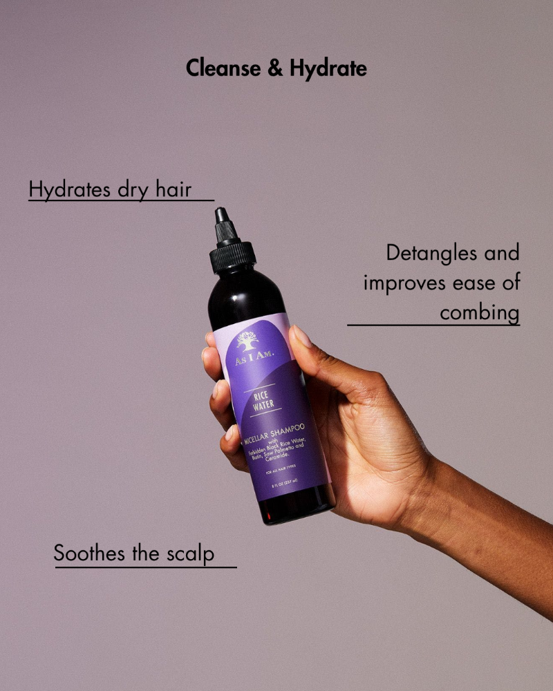 Hand holding a purple shampoo bottle with text about hair care benefits on a gray background