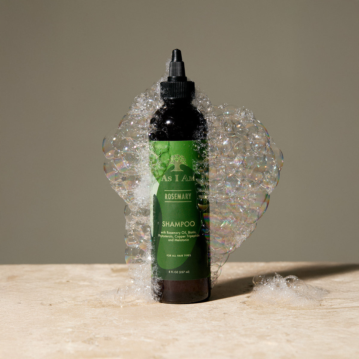 Een fles rozemarijnshampoo met een aanzienlijke hoeveelheid schuim eromheen, wat aangeeft dat het product een vloeistof is.