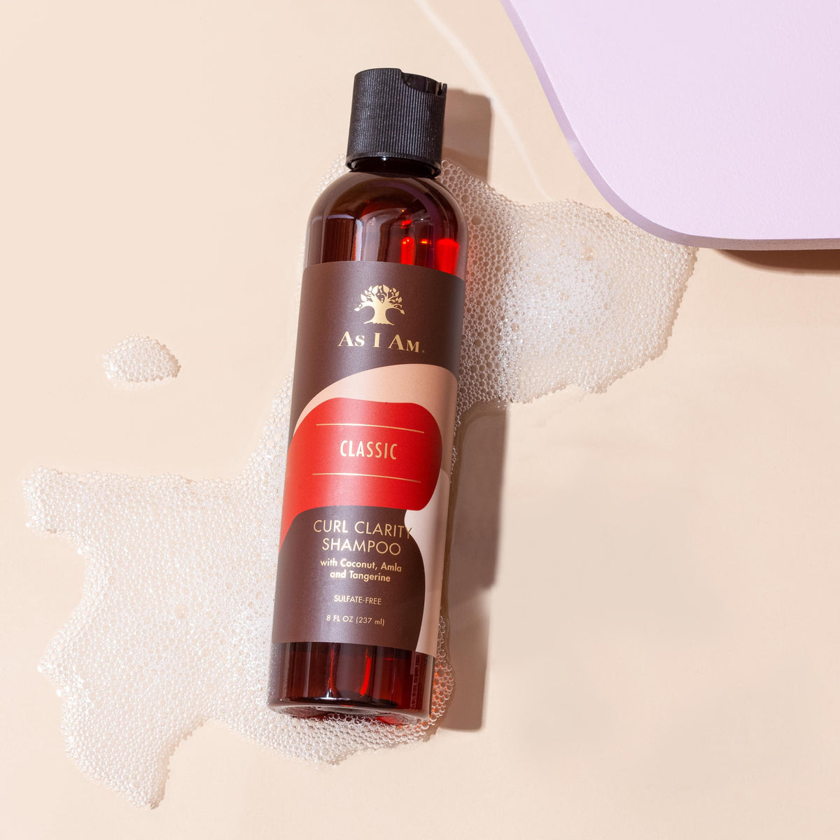 زجاجة من شامبو Curl Clarity ذات ملصق أحمر، موضوعة على سطح محاط بقطرات ماء، مما يشير إلى أن المنتج مخصص للعناية بالشعر.