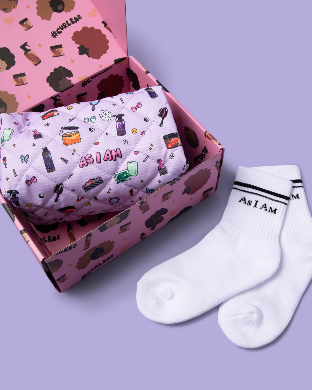 White socks with 'As I Am' text next to a pink box with patterned content on a purple background