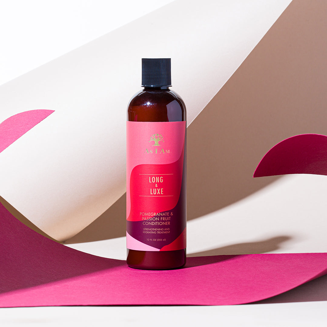 Eine Flasche Long & Luxe Conditioner von Sally mit einem rosa Etikett vor einem Hintergrund mit geometrischem Muster.