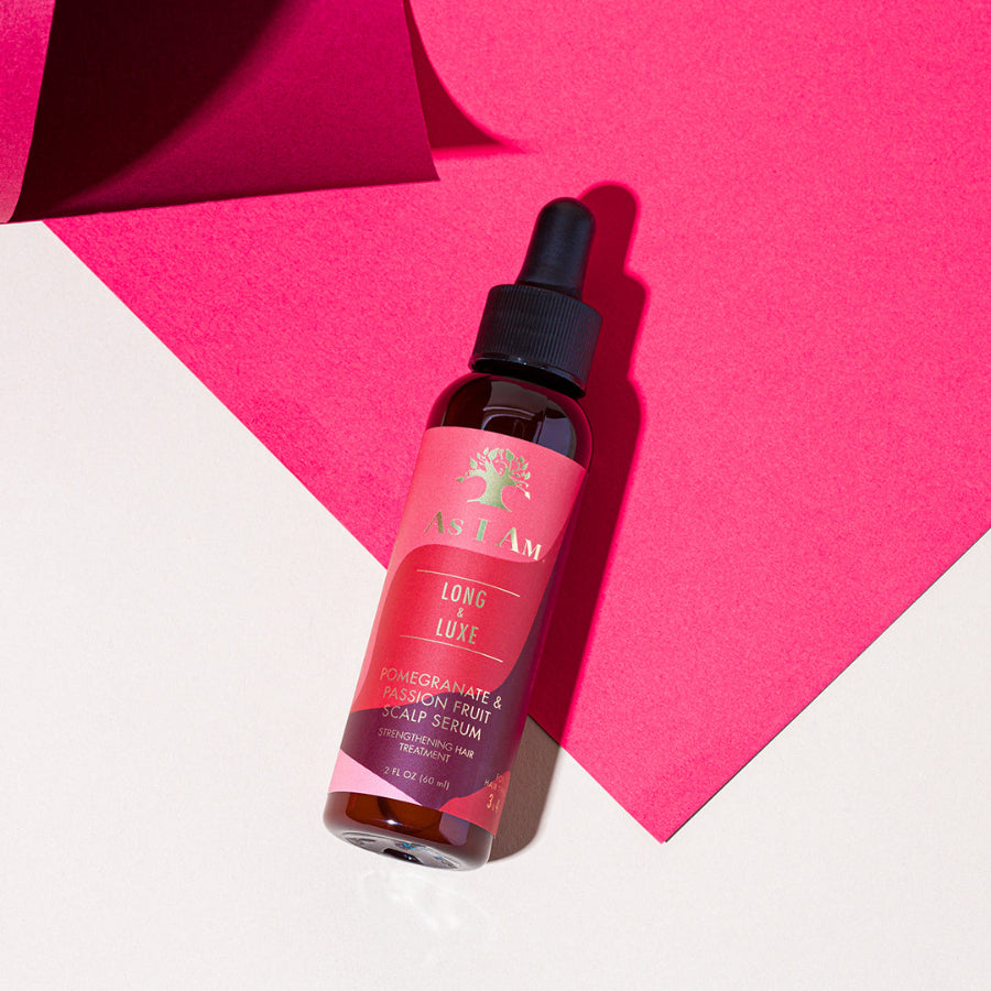 Une bouteille de sérum pour cuir chevelu Long & Luxe avec un bouchon compte-gouttes, placée sur un fond rose vif.