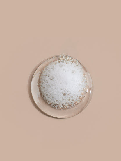 Round glass dish with soapy bubbles on a beige background
