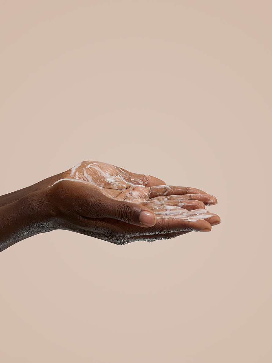 Hand with soap suds on a beige background