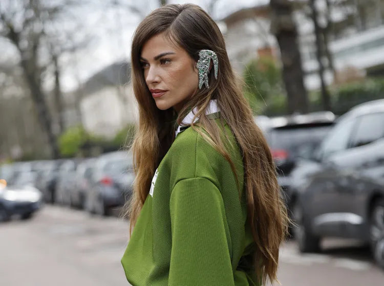 Woman wearing a green outfit with a blurred background of cars and trees