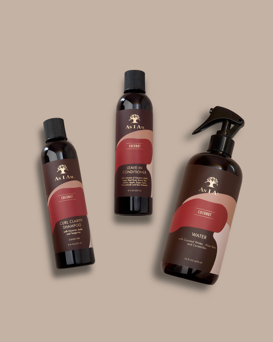 Three bottles of As I Am hair care products on a beige background