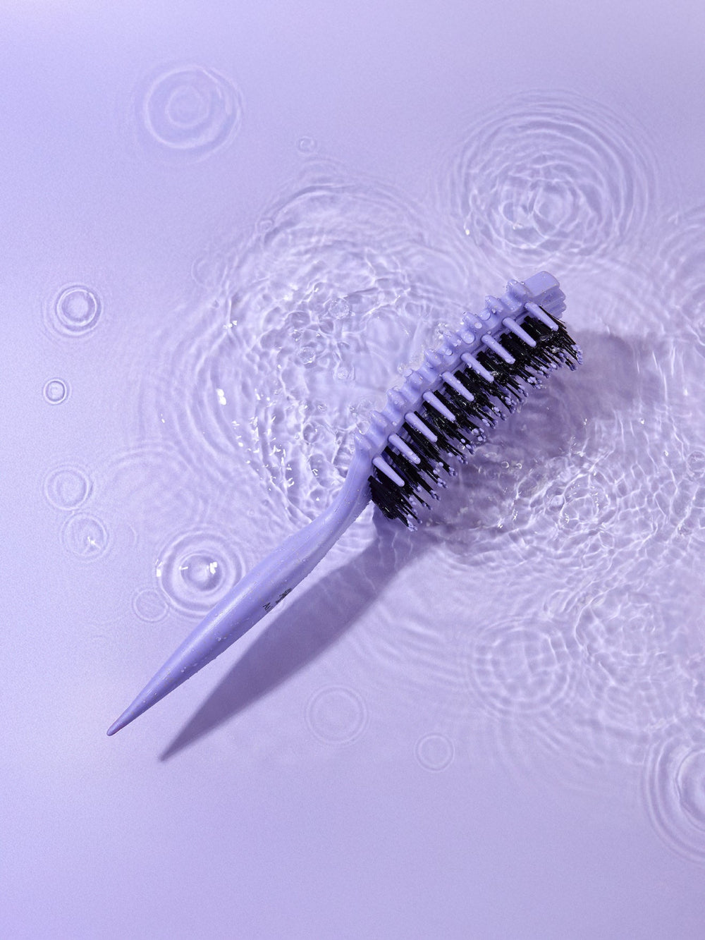 Cleaning brush with bristles on a textured purple surface
