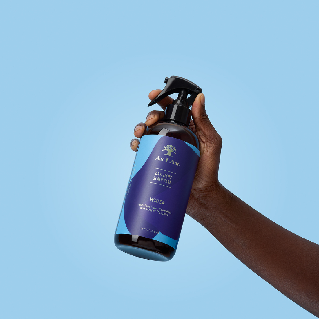 Hand holding a bottle of AS I AM Deodorant Spray against a clear blue background