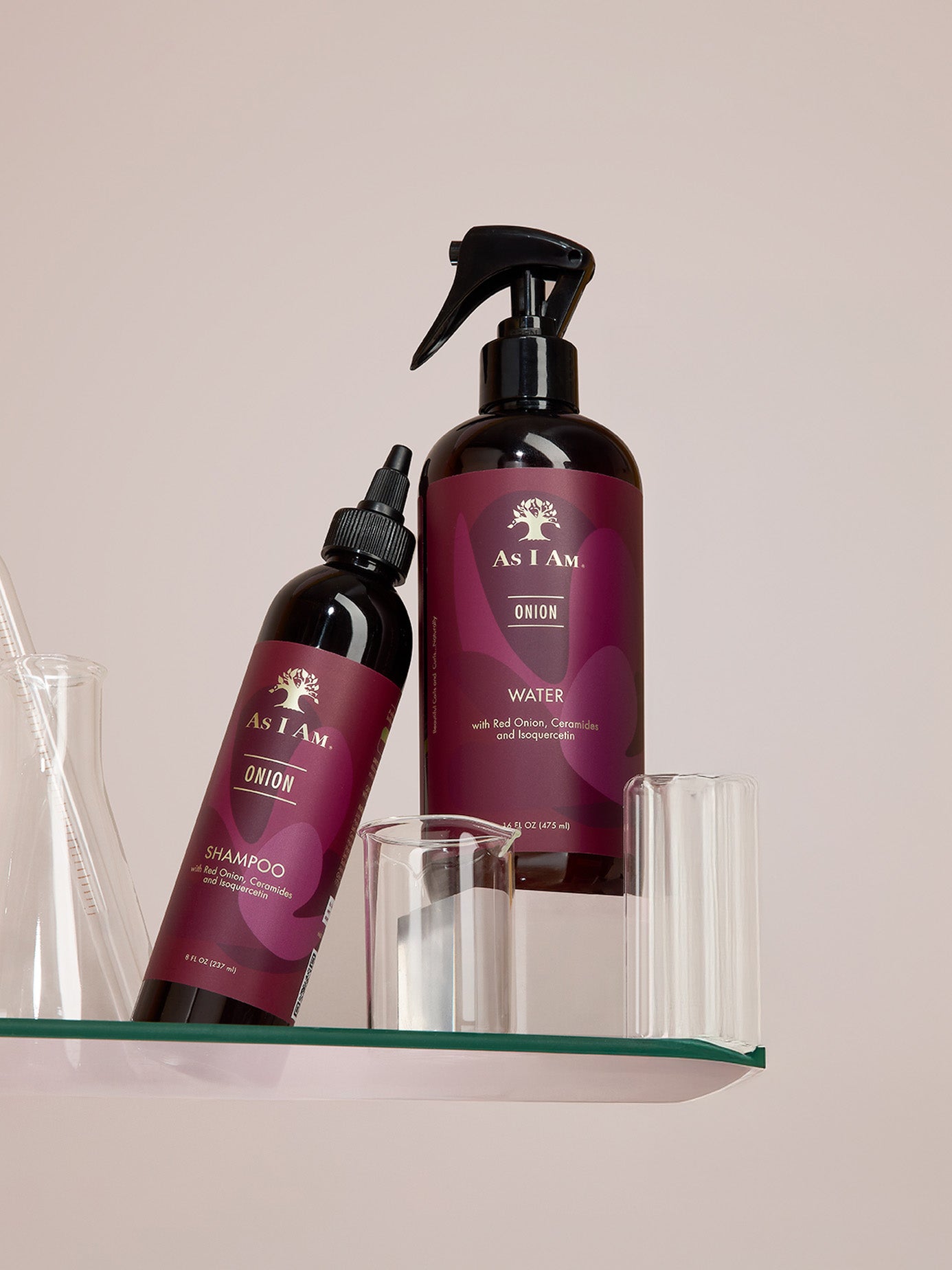 Two bottles of As I Am hair care products on a glass shelf with a neutral background