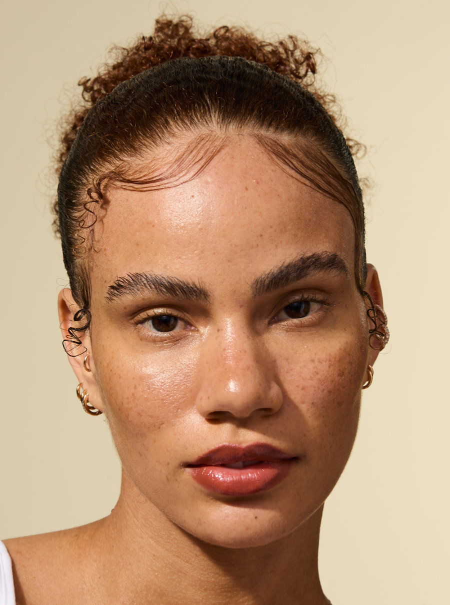 Model with sleek, laid edges and a polished hairstyle styled using the AS I AM Rosemary Wax Stick—hair appears smooth, frizz-free, and firmly held in place with a natural-looking finish.