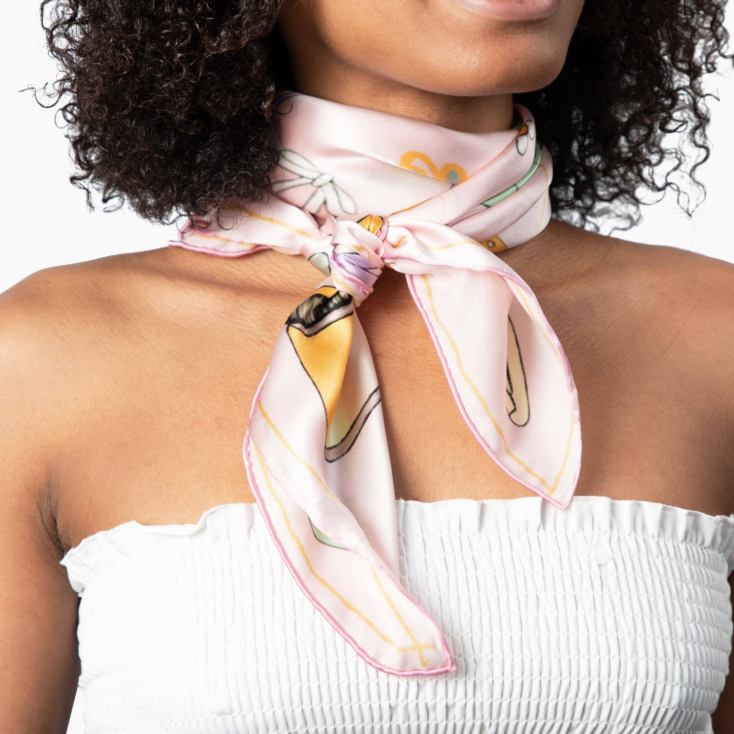 Woman wearing a patterned scarf around her neck with a white top.