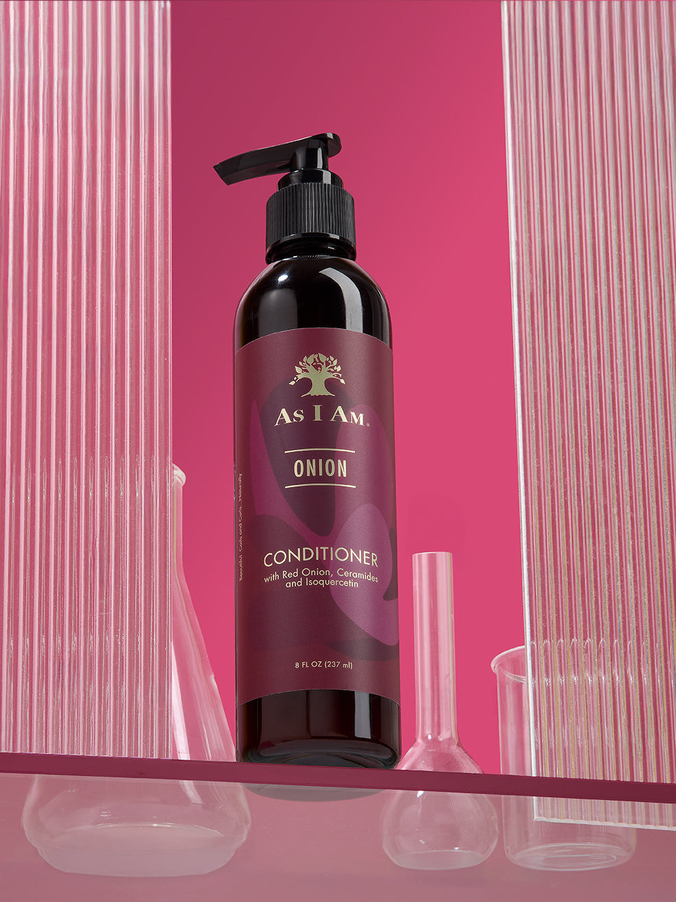 Bottle of 'As I Am Onion' conditioner with a pump on a pink background