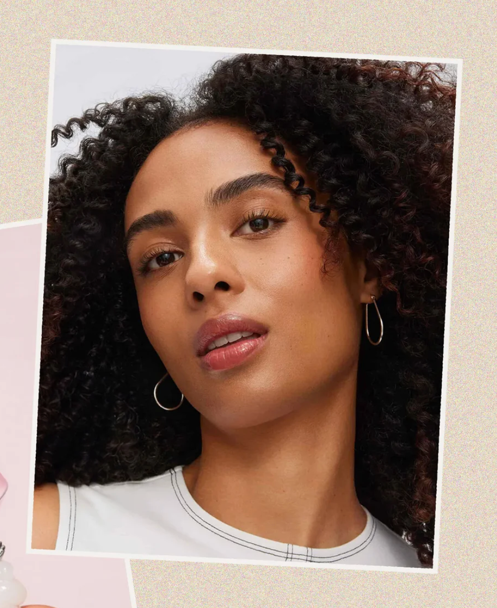 Woman with curly hair wearing hoop earrings on a beige background