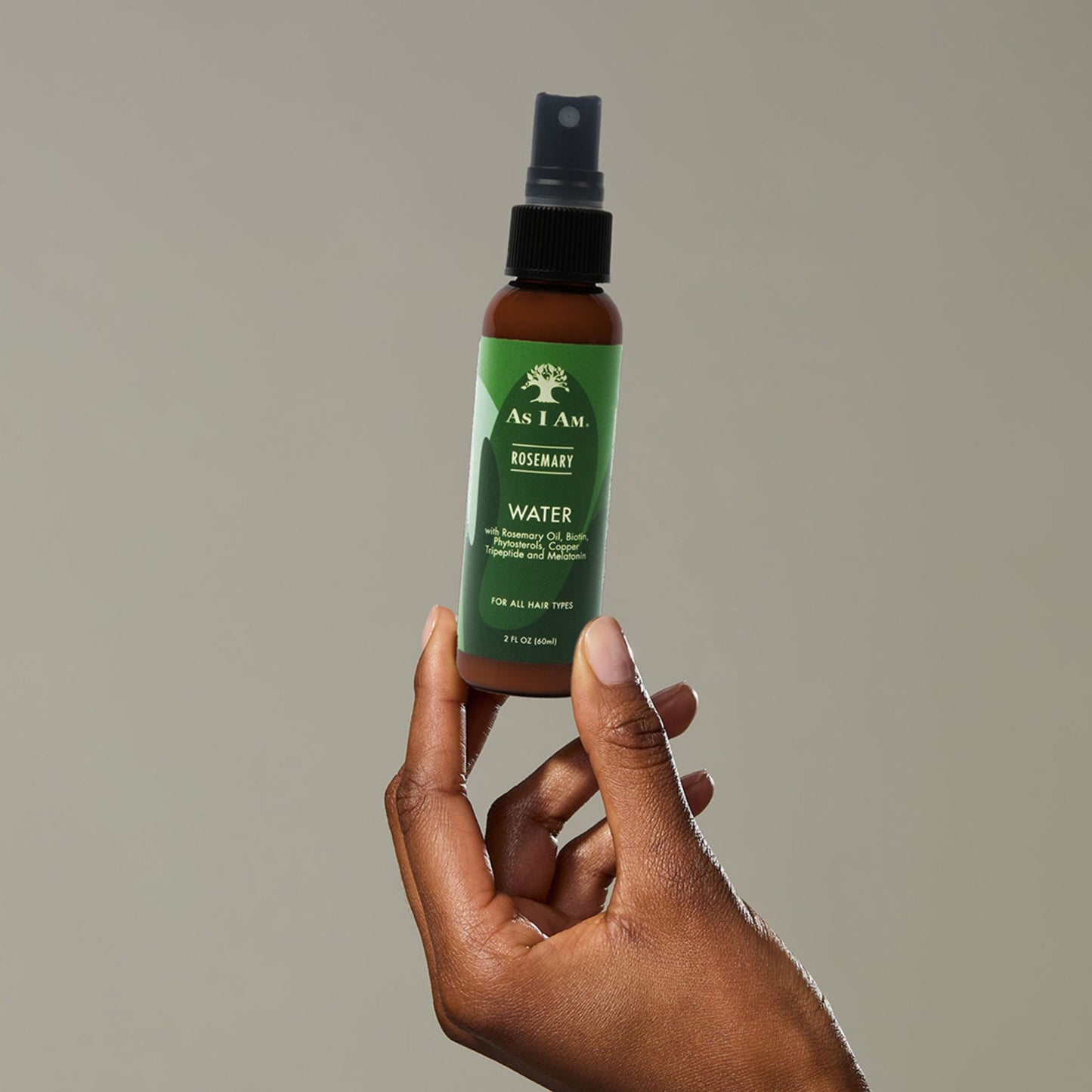 Een hand die een flesje ‘As I Am Rosemary Water’ vasthoudt’ 