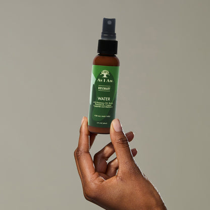 Een hand die een flesje ‘As I Am Rosemary Water’ vasthoudt’ 